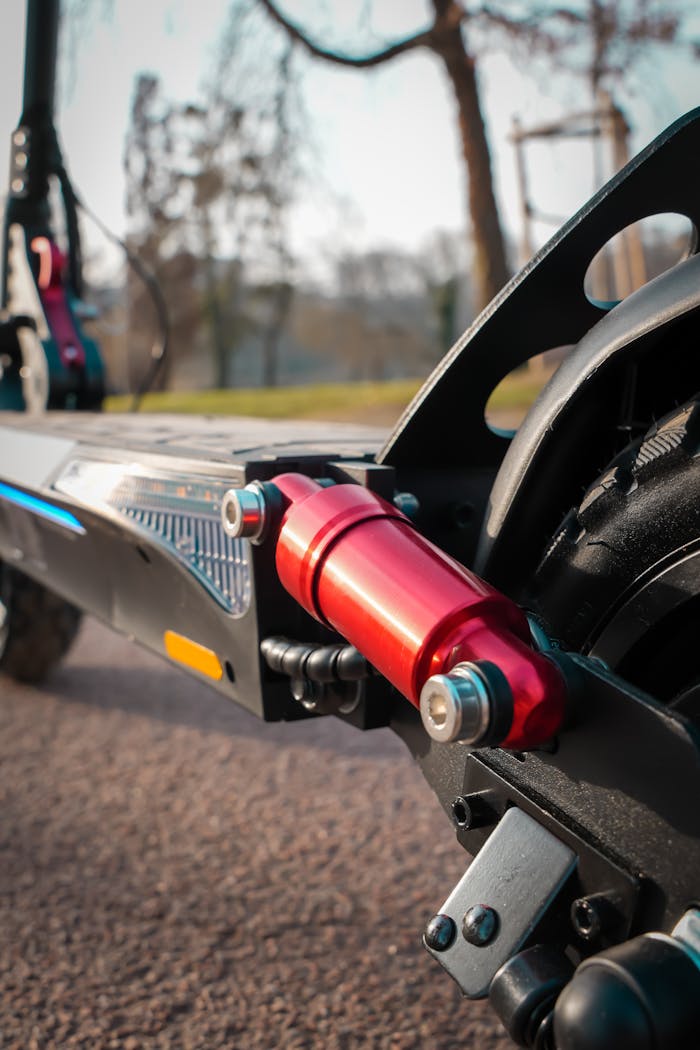 Detailed view of the suspension system on an electric scooter parked outdoors.