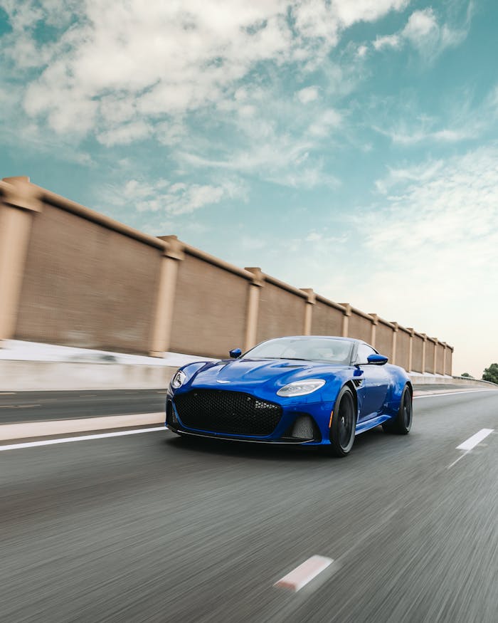 A sleek blue sports car speeds on an open highway, capturing a sense of freedom and speed.